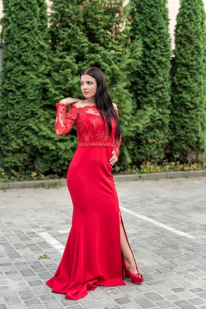 Hermosa morena en vestido rojo contra el paisaje urbano