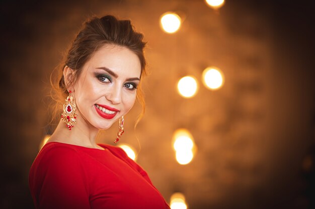 Hermosa morena con un vestido rojo en el fondo del árbol de Navidad.