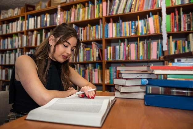 Hermosa morena viene a la biblioteca el fin de semana para leer libros inteligentes El concepto de una mujer en la biblioteca