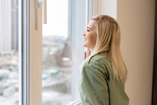 Hermosa mujer abriendo la ventana por la mañana