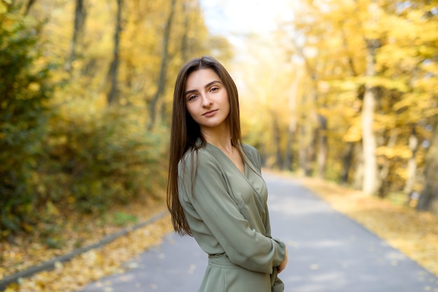 Hermosa mujer en abrigo posando en el bosque en el borde de la carretera