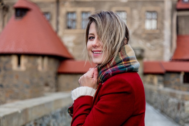 Hermosa mujer en abrigo rojo permanecer cerca del castillo en invierno. Polonia