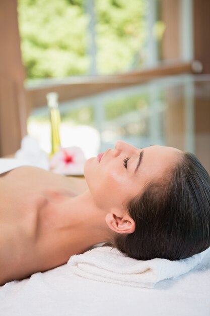 Hermosa mujer acostada en la mesa de masaje en el centro de spa