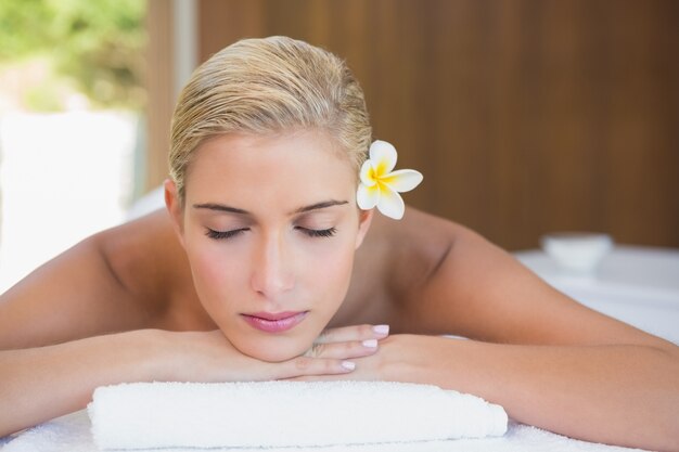 Hermosa mujer acostada en la mesa de masaje en el centro de spa