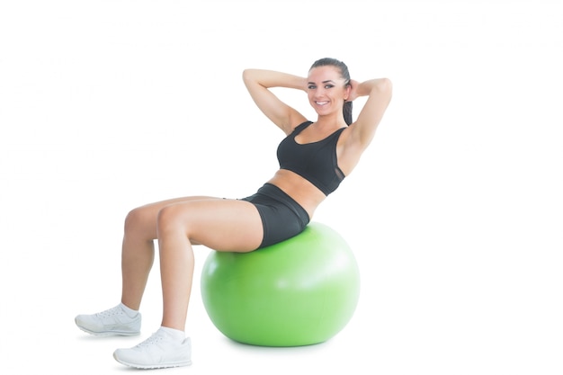 Hermosa mujer activa practicando un ejercicio en una pelota de ejercicios