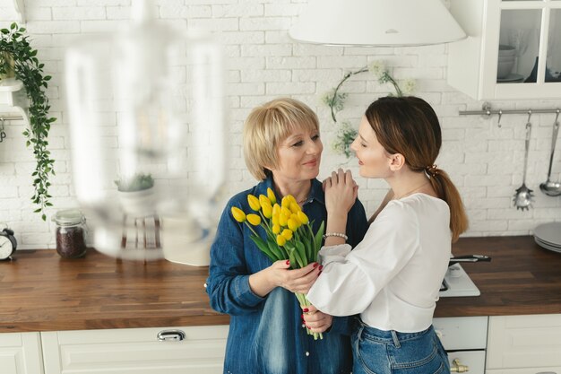 Hermosa mujer adulta dando flores a su madre madura