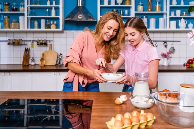 Hermosa mujer adulta e hija para hornear en la cocina