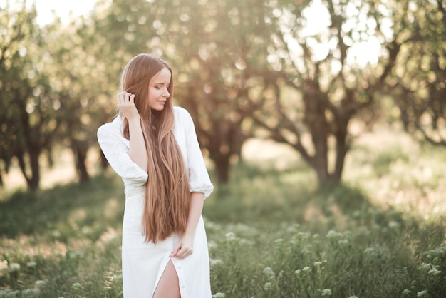 Hermosa mujer adulta joven con largo cabello rubio usar elegante vestido blanco