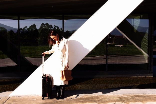 Foto hermosa mujer adulta joven en viaje de negocios esperando transporte en el área de oficinas en la calle