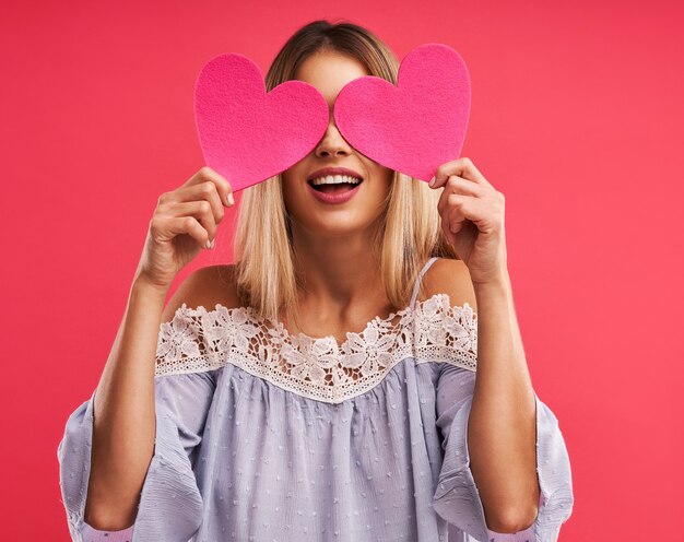 Hermosa mujer adulta posando sobre rosa con corazones