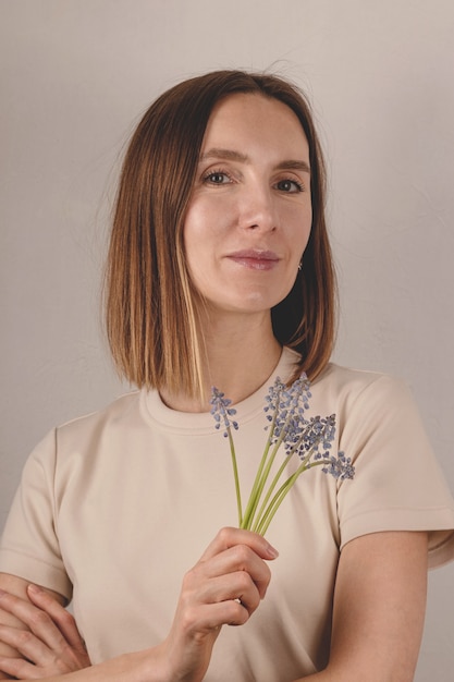 Hermosa mujer adulta sosteniendo flores muscari en sus manos