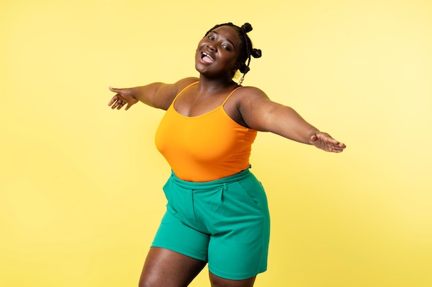 Hermosa mujer africana atractiva de talla grande con ropa casual bailando aislada sobre un fondo amarillo Cuerpo positivo mujer relajante divirtiéndose Estilo de vida positivo