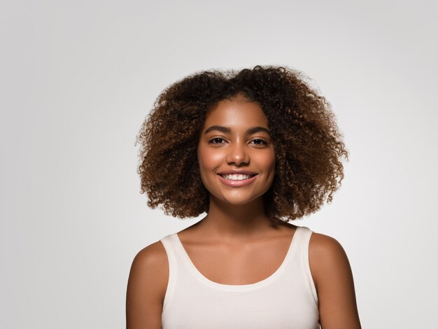 Hermosa mujer africana camiseta blanca retrato afro corte de pelo color de fondo gris