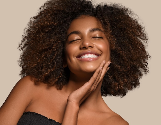 Hermosa mujer africana camiseta negra retrato corte de pelo afro tocando su cara Fondo de color marrón