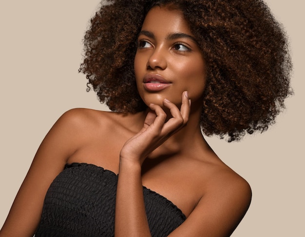 Hermosa mujer africana camiseta negra retrato corte de pelo afro tocando su cara Fondo de color marrón