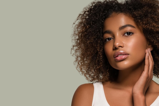 Hermosa mujer africana retrato de camiseta blanca corte de pelo afro tocando su rostro Color de fondo verde