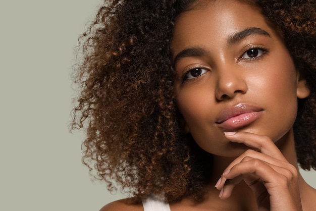 Foto hermosa mujer africana retrato de camiseta blanca corte de pelo afro tocando su rostro color de fondo verde