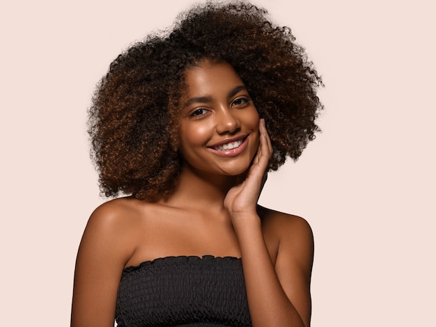 Hermosa mujer africana retrato de camiseta negra corte de pelo afro tocando su rostro Color de fondo rosa