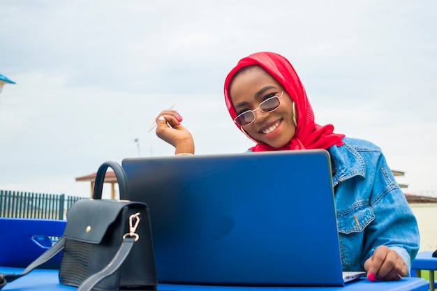 Hermosa mujer africana se siente emocionada por lo que vio en su computadora portátil mientras sostiene su tarjeta de crédito.