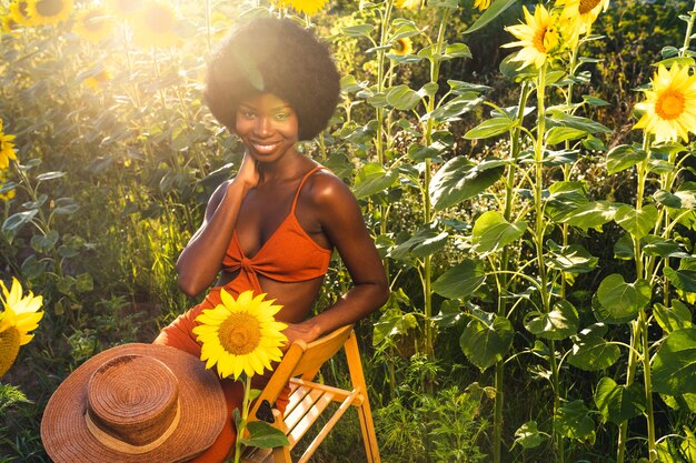 Hermosa mujer afroamericana con cabello rizado estilo afro en un campo de girasoles