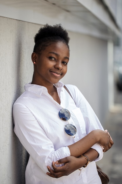 Hermosa mujer afroamericana en la calle contra la pared blanca