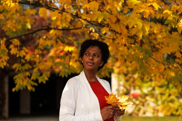 Hermosa mujer afroamericana caminando en un jardín de otoño