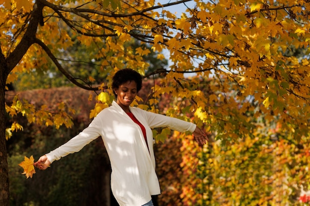 Hermosa mujer afroamericana caminando en un jardín de otoño