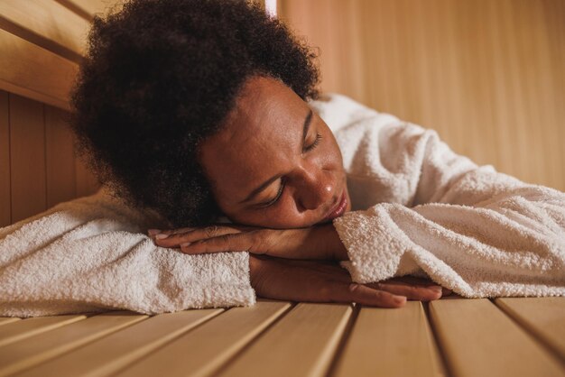 Hermosa mujer afroamericana madura relajándose en una sauna en el centro de spa.