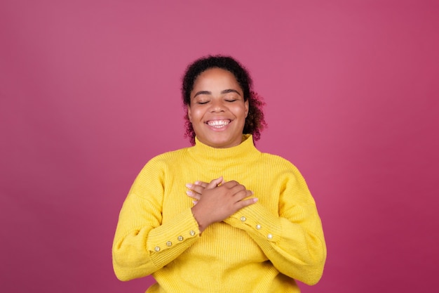 Hermosa mujer afroamericana en pared rosa feliz manos sonrientes en el pecho ámate a ti mismo concepto, autocuidado