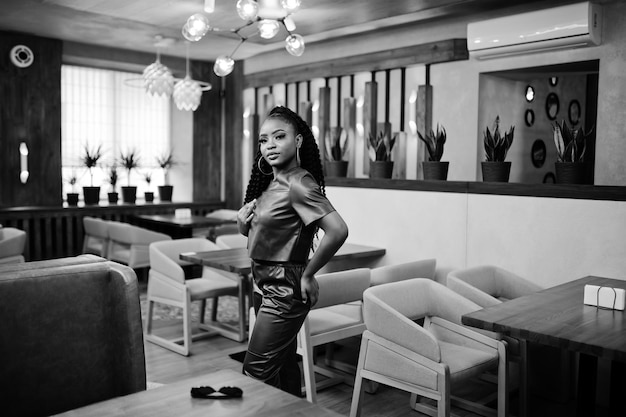 Hermosa mujer afroamericana en pose de traje de cuero rojo en el restaurante