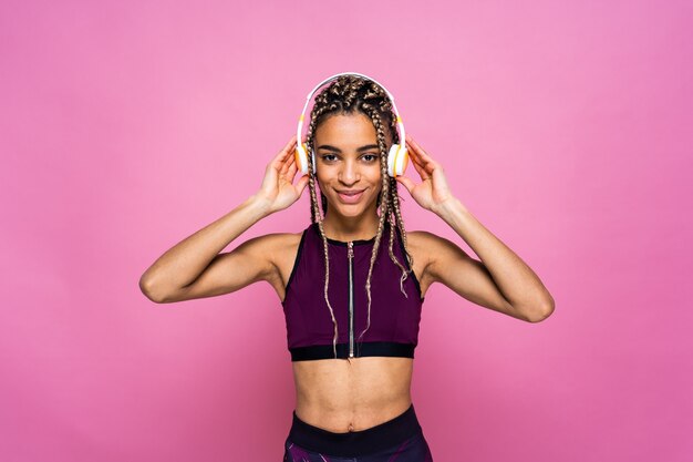 Hermosa mujer afroamericana con retrato de coletas en la pared de color haciendo ejercicios deportivos