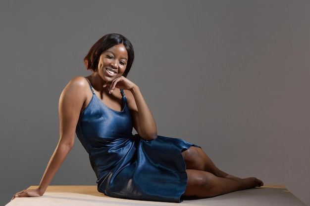 Hermosa mujer afroamericana sonriente con vestido de cóctel siente felicidad posando en el cuerpo del estudio