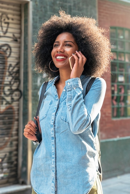 Hermosa mujer afroamericana con su móvil en la calle. Concepto de comunicación.