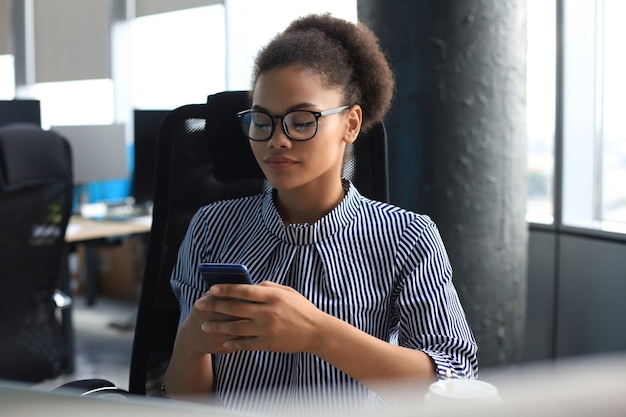 Hermosa mujer afroamericana mediante teléfono móvil. Concepto de comunicación.