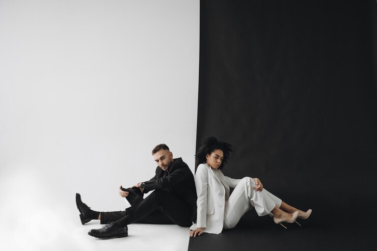 Hermosa mujer afroamericana con traje blanco sentada con un hombre con traje negro sobre fondo blanco negro
