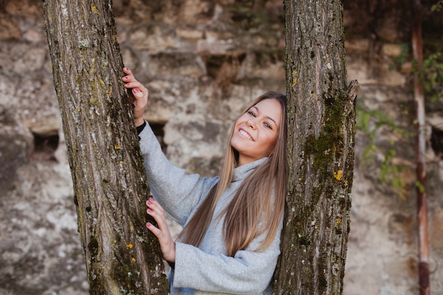 Hermosa mujer al lado del tronco de un árbol.