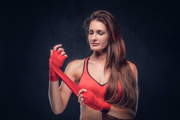 Hermosa mujer alegre en sujetador rojo está usando sus guantes antes de boxear.