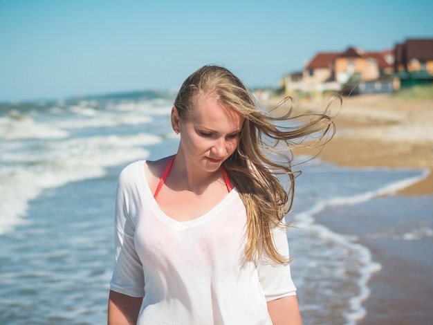 Hermosa mujer con aleteo en el pelo del viento cerca del mar agitado.