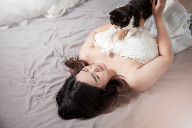 Hermosa mujer amante de los gatos asiáticos está jugando con el gato en su habitación