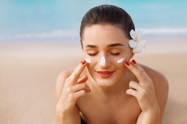 Hermosa mujer aplicando en la cara Retrato facial de mujer Belleza Concepto de cuidado de la piel Crema solar Loción bronceadora