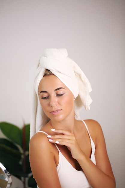 Hermosa mujer aplicando crema cosmética, belleza y salud.