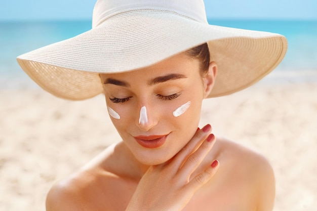 Hermosa mujer aplicando en la hermosa en la cara Protector solar Crema solar Cuidado de la piel Protección solar