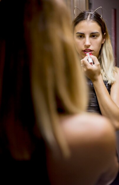 Foto una hermosa mujer aplicando maquillaje en casa.