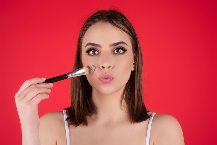 Foto hermosa mujer aplicando maquillaje con cepillo de belleza componen el concepto de un salón de belleza de mujer joven