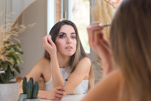 Hermosa mujer aplicándose rímel de pestañas como toque final antes de salir a almorzar