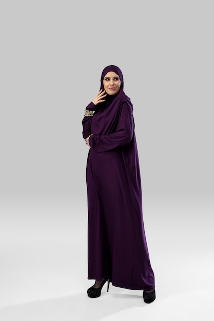 Hermosa mujer árabe posando en elegante hijab aislado sobre fondo de estudio. Concepto de moda