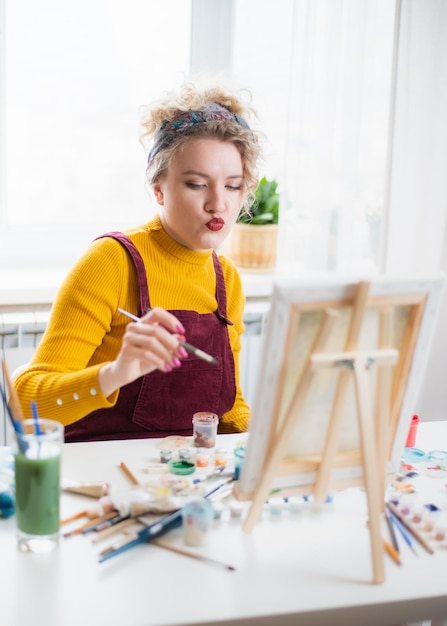 Hermosa mujer artista pinta sobre lienzo en casa