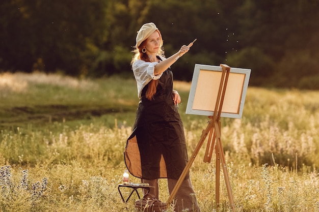 Hermosa mujer artista pintando al atardecer en la naturaleza