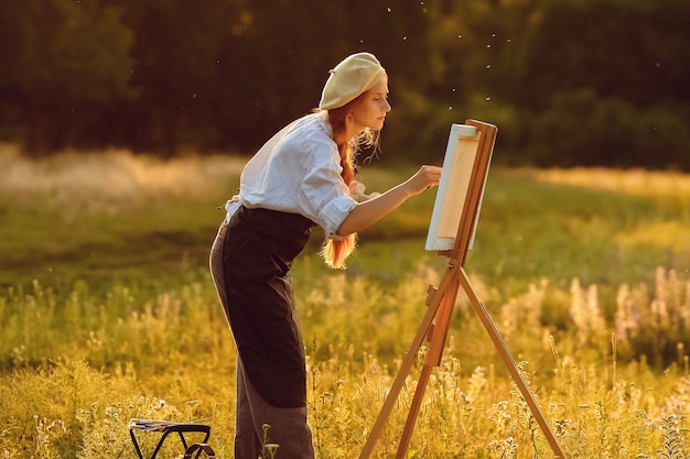 Hermosa mujer artista pintando al atardecer en la naturaleza