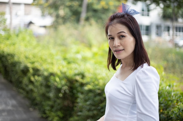 Hermosa mujer asiática de 40 años de edad con fondo de naturaleza al aire libre